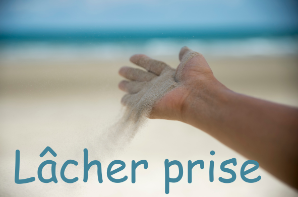 main qui libère du sable sur une plage avec l'océan en arrière plan. Les mots lâcher prise sont écrits